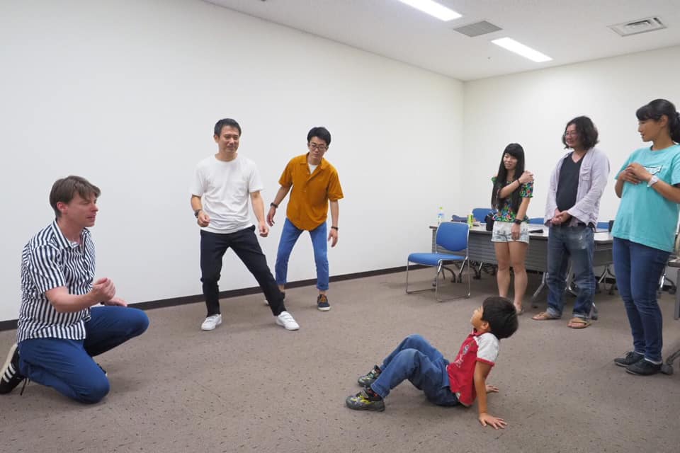 大人と子どもが輪になって即興表現を楽しむ様子