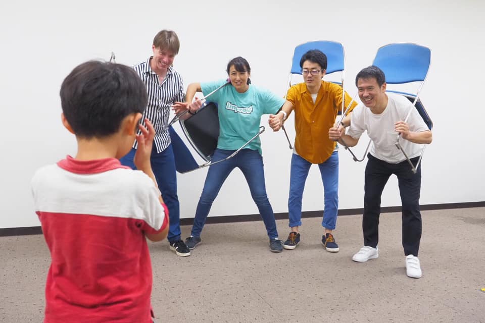 子どもと向き合い、笑顔でポーズをとる参加者たち